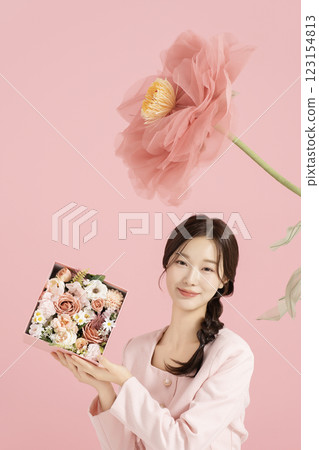 An innocent woman in her 20s wearing a pink two-piece with a large flower in the background. 123154813