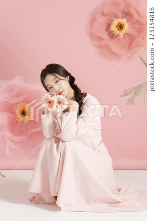 An innocent woman in her 20s wearing a pink two-piece with a large flower in the background. 123154816