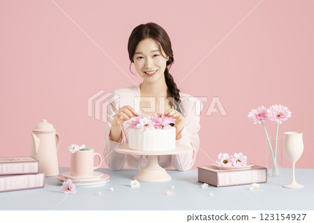 A woman in her 20s smiling brightly while sitting in front of a cake 123154927