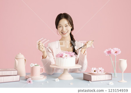 A woman in her 20s sitting in front of a cake holding a fork and knife A woman in her 20s sitting in front of a cake holding a fork and knife 123154939