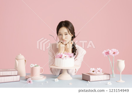 A woman in her 20s sitting in front of a cake holding a fork and knife 123154949