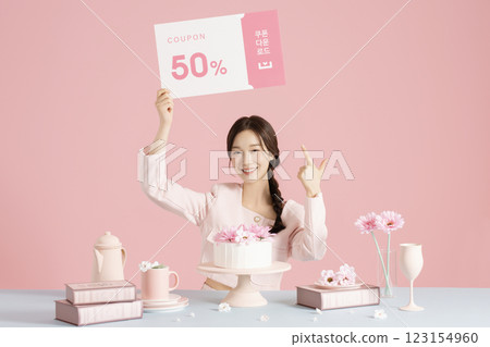 A woman in her 20s sitting in front of a cake and scooping up flowers with a fork. 123154960