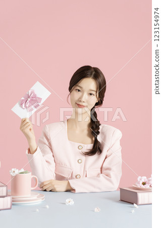 A woman in her 20s holding a beautifully packaged gift certificate 123154974