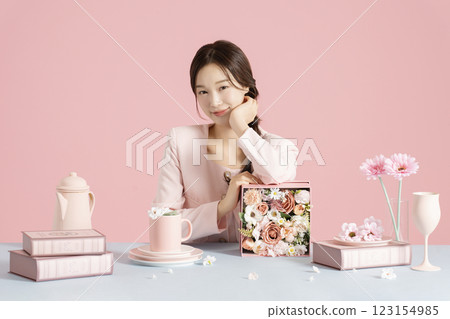 A woman in her 20s smiling while sitting in front of a table set with a bright spring concept. A woman in her 20s smiling while sitting in front of a table set with a bright spring concept. 123154985