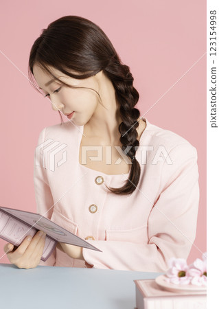 A woman in her 20s reading a pink book A woman in her 20s reading a pink book 123154998