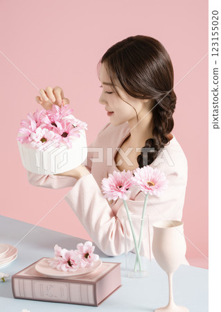 A woman in her 20s posing with a cake while sitting at a table set up with a bright spring concept. A woman in her 20s posing with a cake while sitting at a table set up with a bright spring concept. 123155020