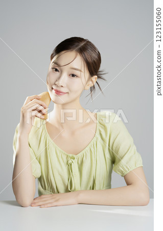 A pretty woman in her 20s wearing bright clothes, sitting and posing with cosmetics A pretty woman in her 20s wearing bright clothes, sitting and posing with cosmetics 123155060