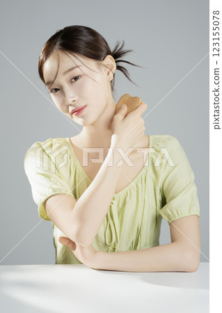 A pretty woman in her 20s wearing bright clothes, sitting and posing with cosmetics 123155078