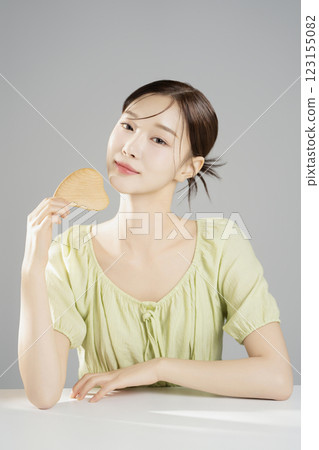 A pretty woman in her 20s wearing bright clothes, sitting and posing with cosmetics 123155082
