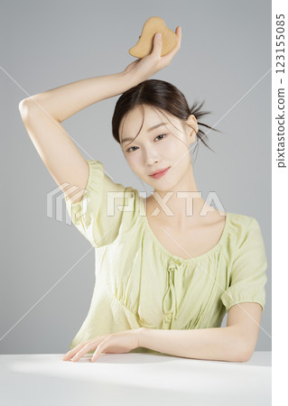 A pretty woman in her 20s wearing bright clothes, sitting and posing with cosmetics A pretty woman in her 20s wearing bright clothes, sitting and posing with cosmetics 123155085
