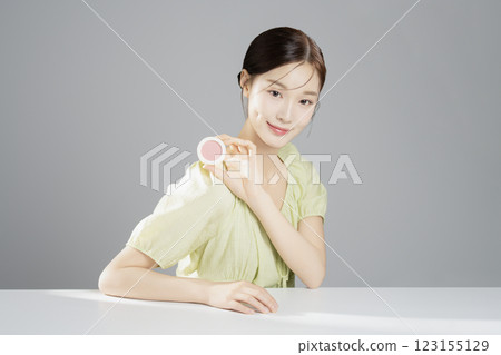 A pretty woman in her 20s wearing bright clothes, sitting and posing with cosmetics A pretty woman in her 20s wearing bright clothes, sitting and posing with cosmetics 123155129