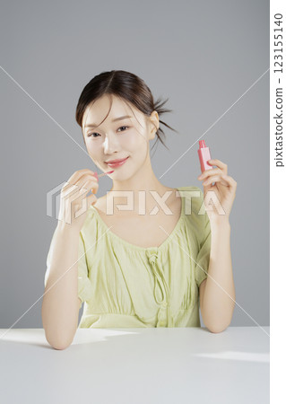 A pretty woman in her 20s wearing bright clothes, sitting and posing with cosmetics 123155140
