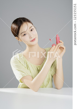 A pretty woman in her 20s wearing bright clothes, sitting and posing with cosmetics 123155151