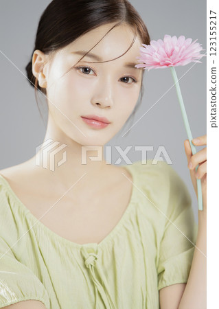 A woman in her 20s posing with a pink flower 123155217