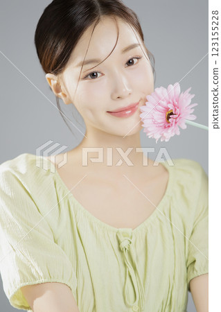 A woman in her 20s posing with a pink flower 123155228