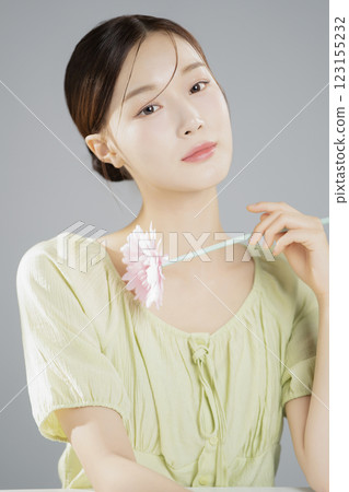 A woman in her 20s posing with a pink flower A woman in her 20s posing with a pink flower 123155232