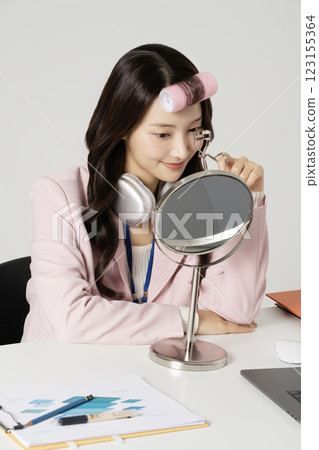 MZ employee fixing her makeup with a hair roller MZ employee fixing her makeup with a hair roller 123155364