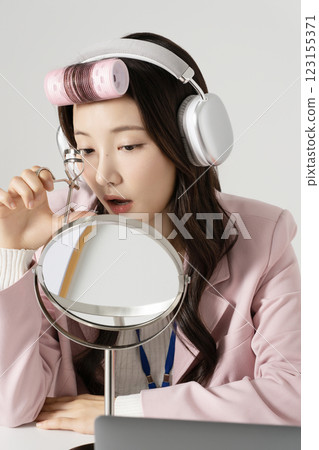 MZ employee fixing her makeup with a hair roller 123155371