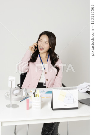 MZ employee in his 20s sitting at his office desk and talking on the phone MZ employee in his 20s sitting at his office desk and talking on the phone 123155563