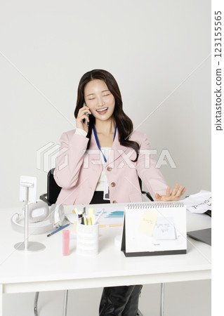 MZ employee in his 20s sitting at his office desk and talking on the phone 123155565