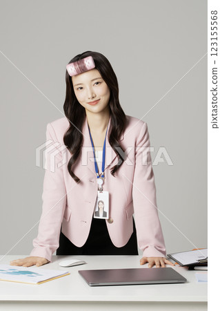 MZ employee in his 20s standing in front of his office desk wearing a hair roll 123155568