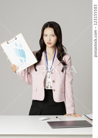 MZ employee in his 20s standing in front of his office desk holding documents MZ employee in his 20s standing in front of his office desk holding documents 123155583