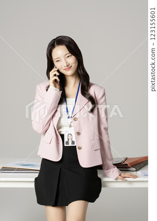 MZ employee in his 20s standing in front of his office desk and talking on the phone 123155601