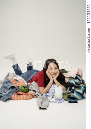 A woman in her 20s lying on a pile of clothes A woman in her 20s lying on a pile of clothes 123155831