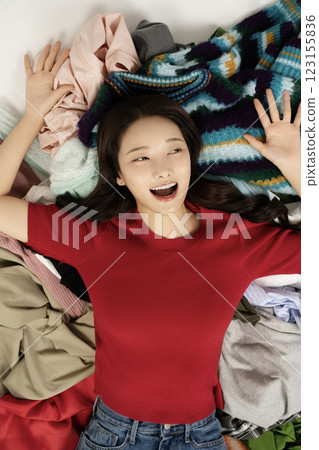 A woman in her 20s lying on a pile of clothes 123155836