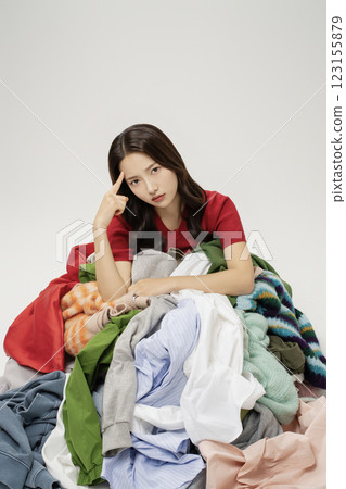A woman in her 20s buried in a mountain of clothes. A woman in her 20s buried in a mountain of clothes. 123155879