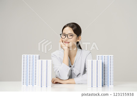 A young woman in her 20s sitting in front of a table with an apartment model set up. 123155938