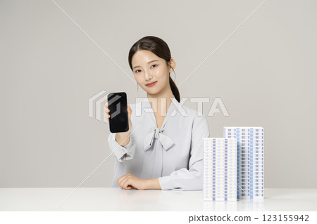 Young woman in her 20s sitting at a table holding a smart phone 123155942