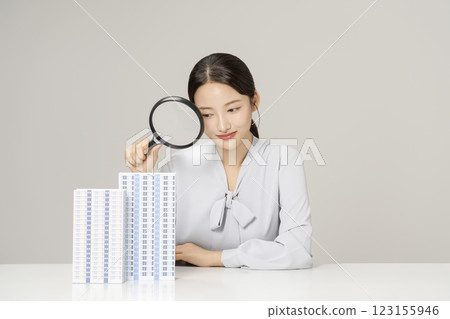 Young woman in her 20s holding a magnifying glass and observing an apartment model Young woman in her 20s holding a magnifying glass and observing an apartment model 123155946