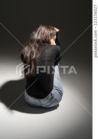 A woman squatting in a lighted area A woman squatting in a lighted area 123156027