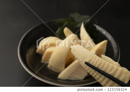 用筷子夾起煮熟的嫩竹筍 用筷子夾起煮熟的嫩竹筍 123156324