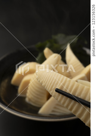 用筷子夾起煮熟的嫩竹筍 用筷子夾起煮熟的嫩竹筍 123156326