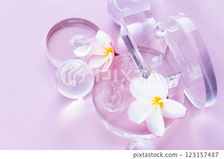 Soft pastel background showcases aloe and centella serum alongside clear decor and delicate flowers. Soft pastel background showcases aloe and centella serum alongside clear decor and delicate flowers. 123157487