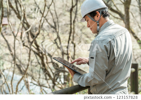 A forestry worker in work clothes checking trees in a park/forest 123157828
