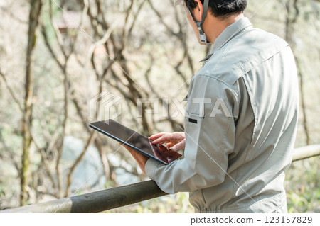 A forestry worker in work clothes checking trees in a park/forest 123157829