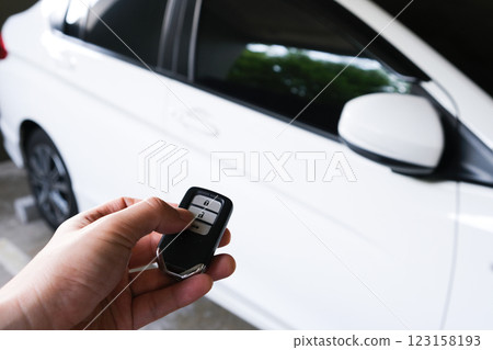 Man hand holding the car remote, he push the remote control to open the car door Man hand holding the car remote, he push the remote control to open the car door 123158193