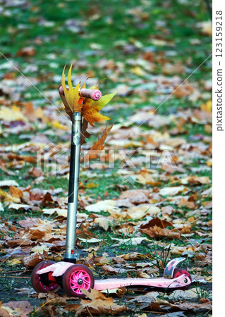 Children's scooter with yellow leaves in the autumn park Children's scooter with yellow leaves in the autumn park 123159218