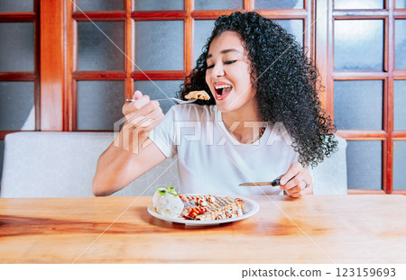 Beautiful girl eating chocolate crepe and ice cream with a fork. Hungry woman sitting eating chocolate crepe and ice cream Beautiful girl eating chocolate crepe and ice cream with a fork. Hungry woman sitting eating chocolate crepe and ice cream 123159693