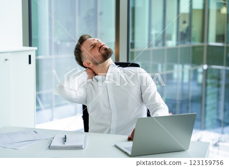 Professional Male Experiencing Neck Strain at Modern Office Desk Workspace 123159756