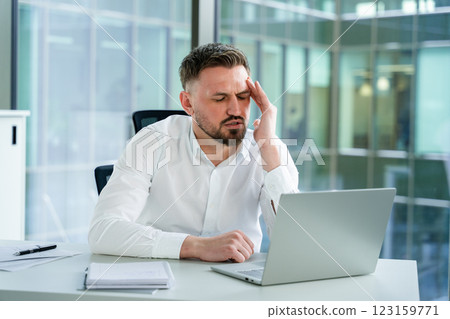Frustrated Businessman Working on Laptop in Office Setting 123159771
