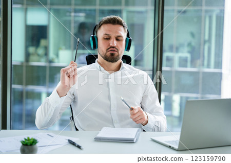 Professional Businessman Working in an Office While Listening to Music Professional Businessman Working in an Office While Listening to Music 123159790