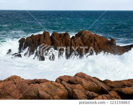 Waves crashing against rocky coastline with blue ocean sky Waves crashing against rocky coastline with blue ocean sky 123159863