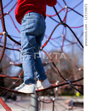 Young caucasian child climbing rope playground structure on a sunny day 123159872