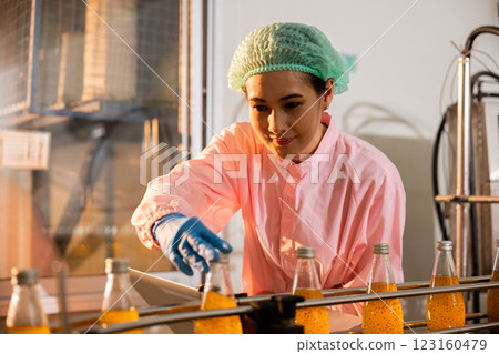 Quality control manager a woman oversees liquid quality by examining beverage bottles on a conveyor belt with a laptop in the factory. Quality control manager a woman oversees liquid quality by examining beverage bottles on a conveyor belt with a laptop in the factory. 123160479