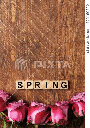 Word Spring in English made of wooden blocks with pink roses on a brown wooden background. Space for your text. Word Spring in English made of wooden blocks with pink roses on a brown wooden background. Space for your text. 123160530
