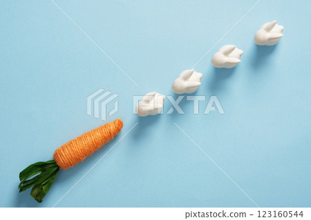 Funny easter concept: bunnies follow carrots on blue background. Space for your text. 123160544